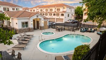 A swimming pool surrounded by lounge chairs and umbrellas in a residential area.